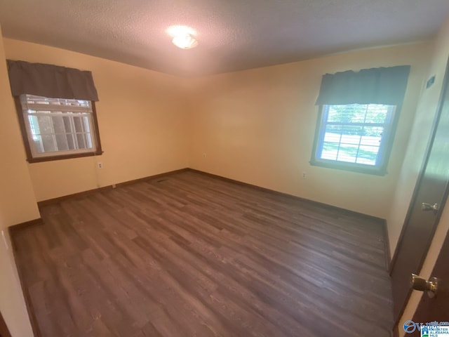 empty room featuring dark hardwood / wood-style flooring and a textured ceiling