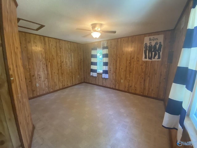 spare room featuring ceiling fan and wooden walls