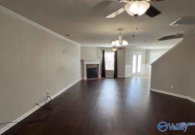 unfurnished living room featuring dark hardwood / wood-style flooring, crown molding, a fireplace, and ceiling fan with notable chandelier