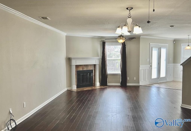 unfurnished living room featuring crown molding, dark hardwood / wood-style flooring, a tile fireplace, and a textured ceiling