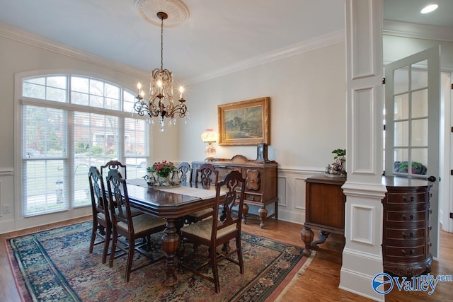 dining room with hardwood / wood-style floors, a wealth of natural light, crown molding, and decorative columns