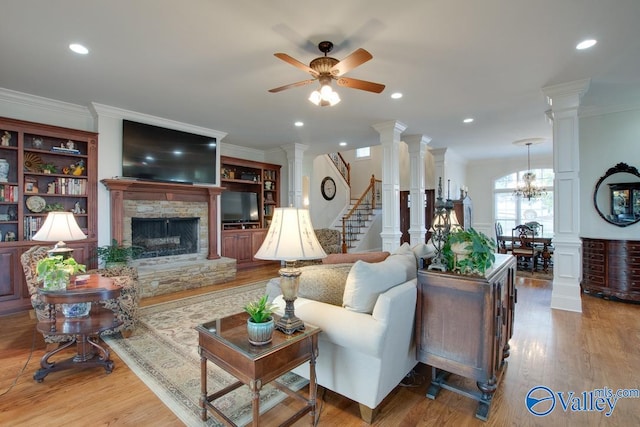 living room featuring ceiling fan with notable chandelier, light hardwood / wood-style floors, a fireplace, and crown molding