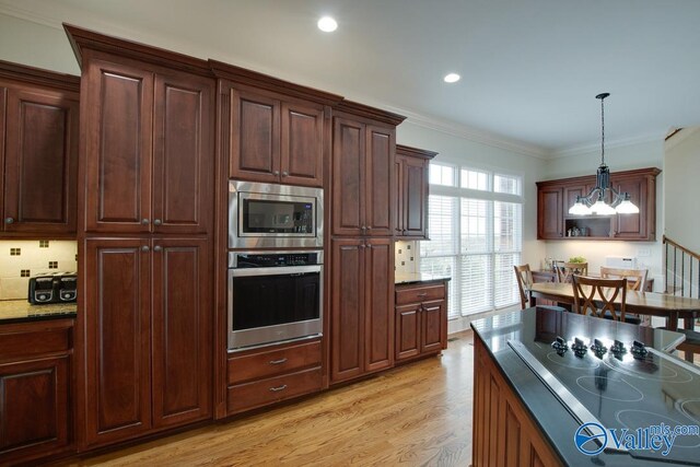 kitchen with light hardwood / wood-style floors, a chandelier, ornamental molding, pendant lighting, and appliances with stainless steel finishes