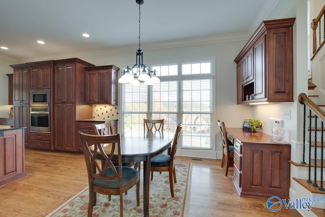 dining area featuring light wood-type flooring, a notable chandelier, and crown molding