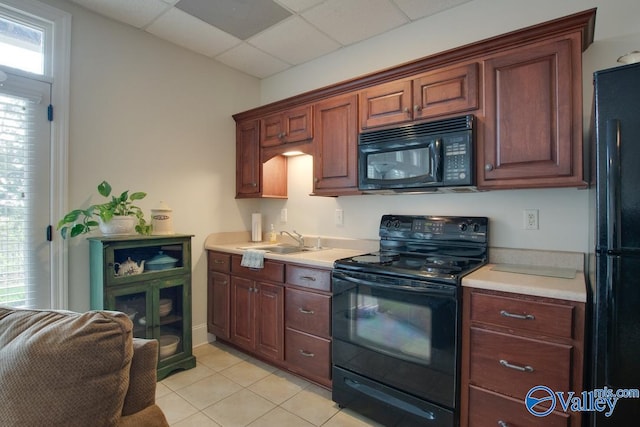 kitchen featuring light tile patterned floors, black appliances, sink, and a drop ceiling