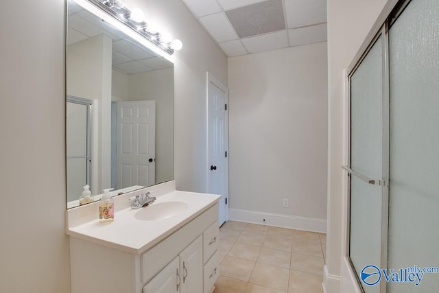 bathroom featuring a paneled ceiling, vanity, tile patterned floors, and a shower with shower door