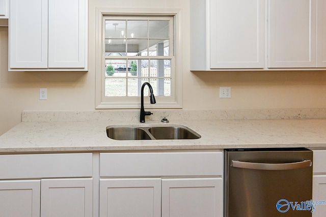 kitchen with dishwasher, light stone counters, a sink, and white cabinetry