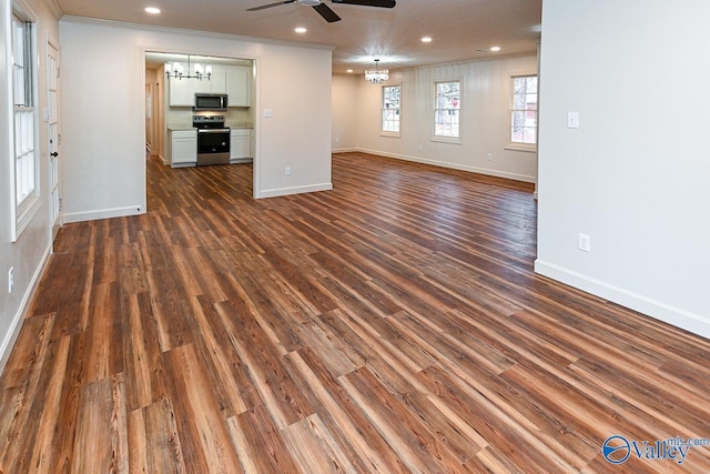 unfurnished living room featuring baseboards, dark wood-type flooring, ceiling fan with notable chandelier, crown molding, and recessed lighting