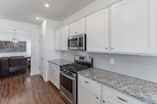 kitchen featuring light stone counters, dark wood-type flooring, white cabinetry, stainless steel appliances, and an inviting chandelier