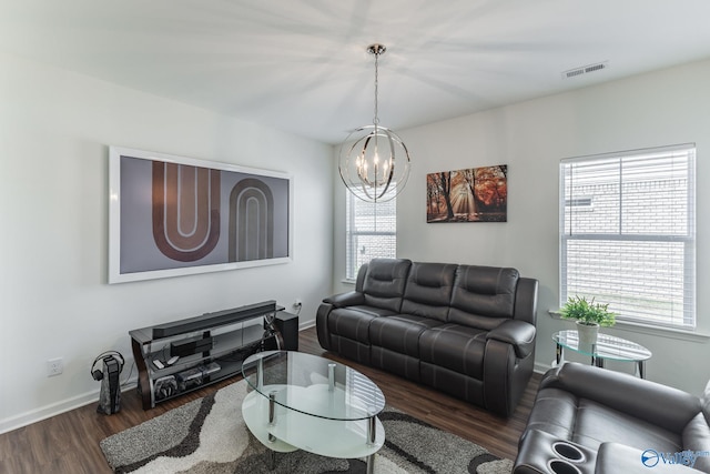 living room featuring a notable chandelier, plenty of natural light, and dark wood-type flooring