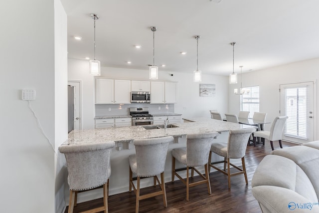 kitchen featuring appliances with stainless steel finishes, a kitchen breakfast bar, pendant lighting, and white cabinets