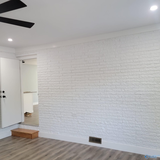 unfurnished room with hardwood / wood-style flooring and brick wall