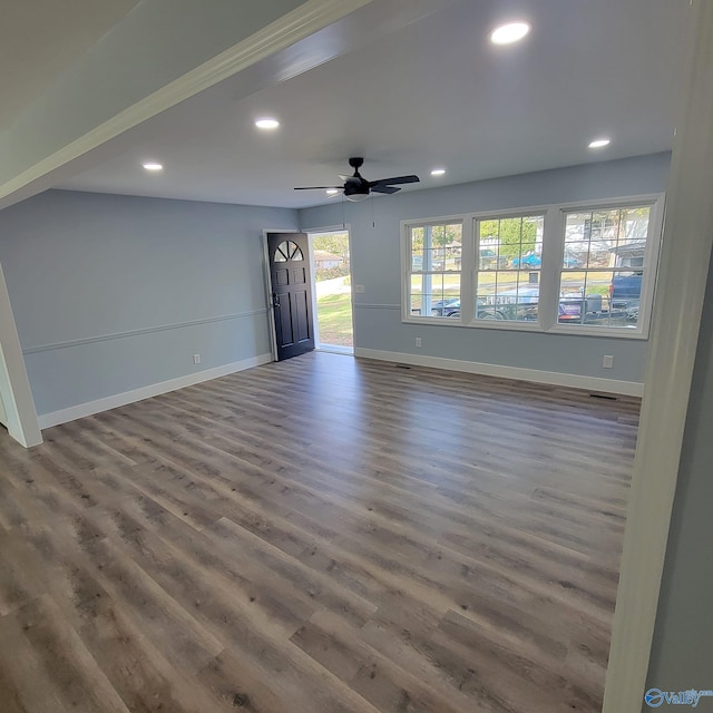 unfurnished living room with ceiling fan and dark wood-type flooring