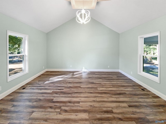 spare room with lofted ceiling, dark hardwood / wood-style floors, and a chandelier