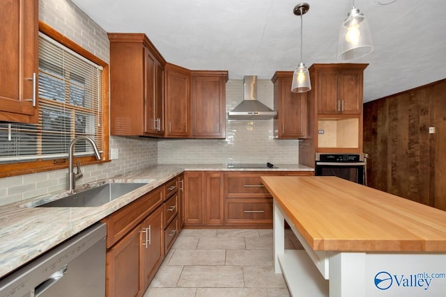 kitchen with sink, wall chimney exhaust hood, decorative backsplash, appliances with stainless steel finishes, and butcher block countertops