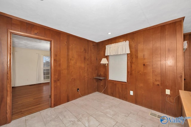 unfurnished room with wood walls and light wood-type flooring