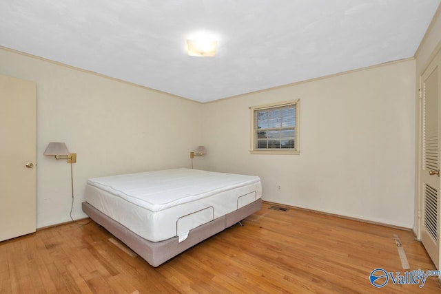 bedroom with light hardwood / wood-style floors and crown molding