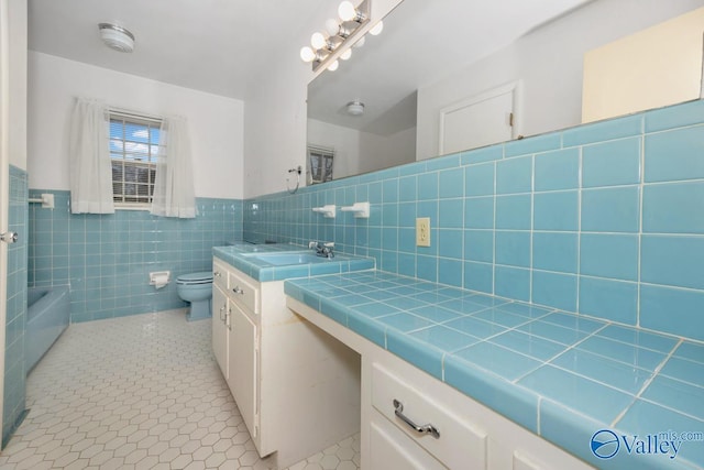 bathroom with a bathing tub, tile patterned flooring, toilet, vanity, and tile walls