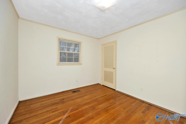 unfurnished room featuring wood-type flooring and crown molding