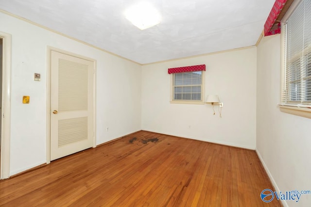 empty room with hardwood / wood-style flooring and ornamental molding