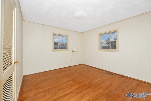 spare room featuring wood-type flooring and ornamental molding