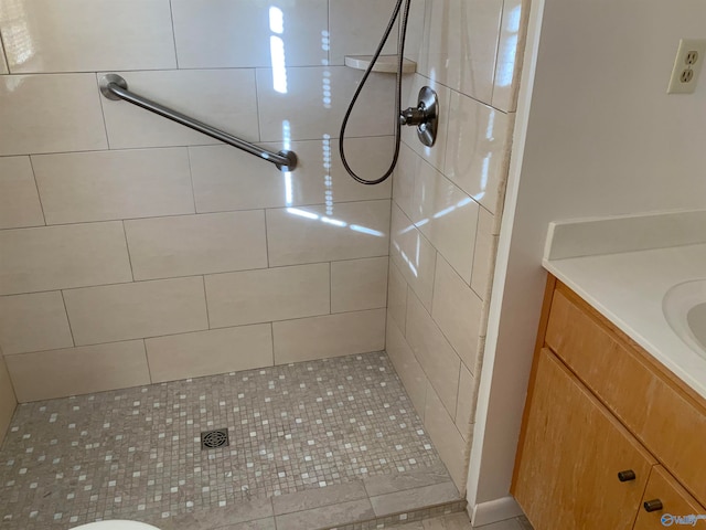 bathroom with tile patterned floors, vanity, and tiled shower