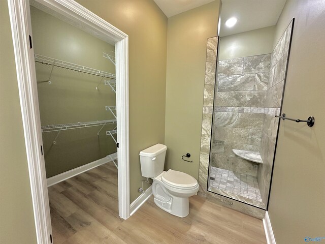 bathroom with hardwood / wood-style floors, toilet, and a tile shower