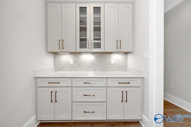 bar featuring white cabinetry, wood-type flooring, and decorative backsplash