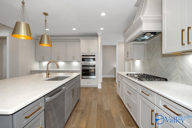 kitchen featuring appliances with stainless steel finishes, tasteful backsplash, sink, light stone counters, and custom range hood