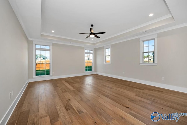 unfurnished room featuring light hardwood / wood-style flooring, ornamental molding, a raised ceiling, and ceiling fan