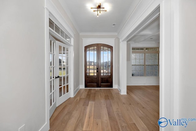 entrance foyer with french doors, crown molding, and light hardwood / wood-style floors