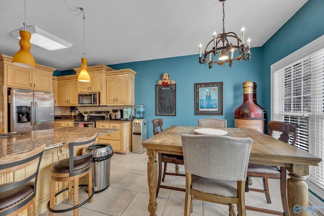 kitchen with appliances with stainless steel finishes, light brown cabinets, hanging light fixtures, and a healthy amount of sunlight