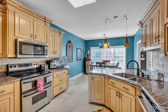 kitchen featuring sink, dark stone countertops, appliances with stainless steel finishes, decorative light fixtures, and light tile patterned flooring