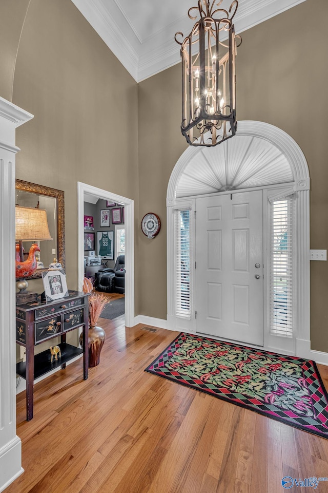 foyer entrance featuring light hardwood / wood-style flooring, crown molding, and a notable chandelier