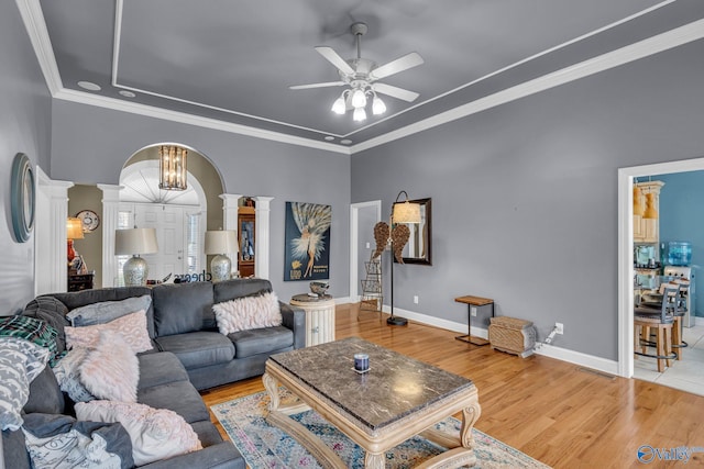 living room with wood-type flooring, ceiling fan with notable chandelier, decorative columns, and ornamental molding