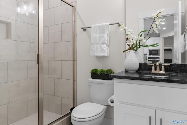 bathroom featuring toilet, a shower stall, and vanity