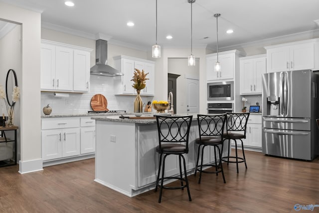 kitchen with stainless steel appliances, wall chimney range hood, a kitchen island with sink, and white cabinets