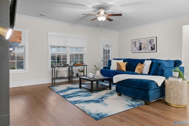 living area featuring crown molding, visible vents, ceiling fan, wood finished floors, and baseboards