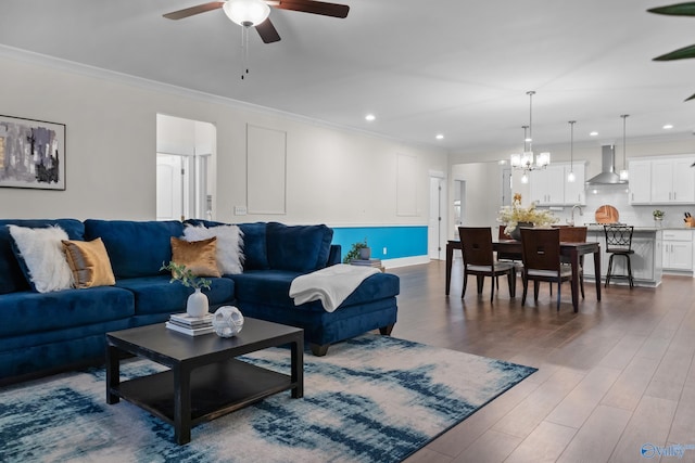 living area with dark wood-style floors, recessed lighting, ceiling fan with notable chandelier, and crown molding