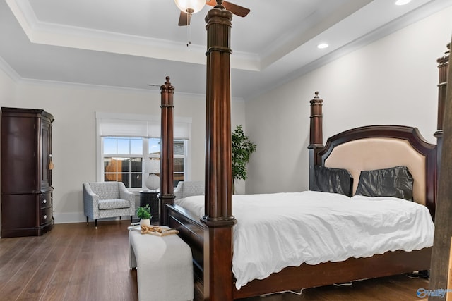 bedroom featuring ornamental molding, a tray ceiling, wood finished floors, and baseboards