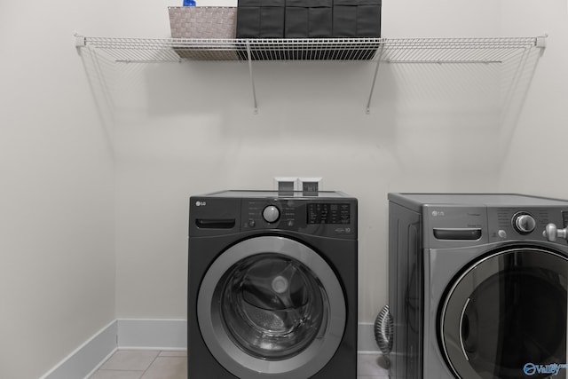 washroom with tile patterned flooring, laundry area, washer and clothes dryer, and baseboards