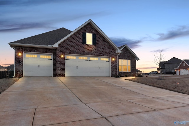 traditional-style home featuring an attached garage, driveway, brick siding, and a shingled roof