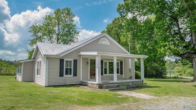 view of front of home featuring covered porch, metal roof, and a front yard