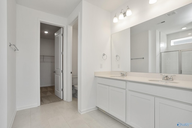 bathroom featuring a shower with door, vanity, tile patterned floors, and toilet