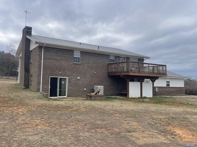 rear view of property with brick siding, metal roof, a chimney, and a wooden deck