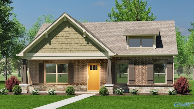 view of front facade with a front yard, a shingled roof, and brick siding