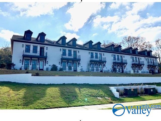 back of property with a balcony, a water view, and a yard