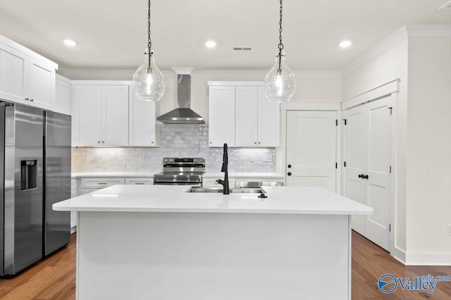 kitchen featuring appliances with stainless steel finishes, light countertops, a sink, and wall chimney range hood