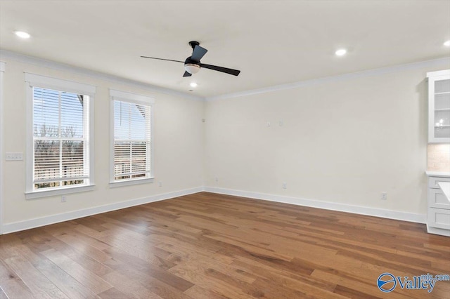 spare room featuring crown molding, recessed lighting, a ceiling fan, wood finished floors, and baseboards