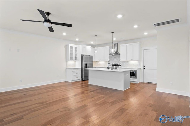 kitchen with visible vents, light countertops, appliances with stainless steel finishes, wall chimney range hood, and tasteful backsplash